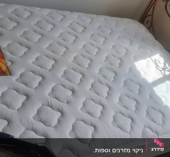 מזרן עם ציוד ניקוי לידו בחדר מואר.